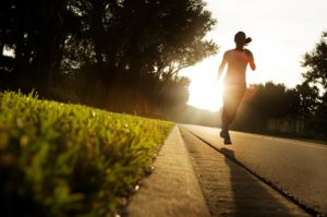 young woman running on rural road at sunrise