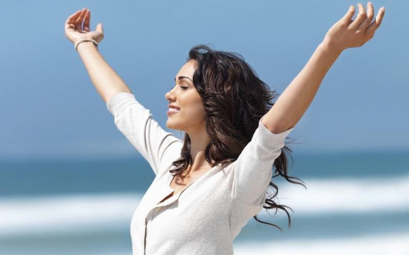 happy-woman-arms-outstretched-beach